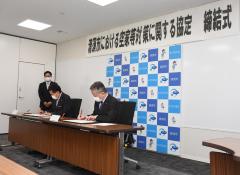 署名をする永田市長（右）と萩原本部長（中央）画像